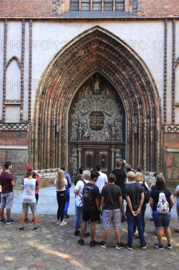 Tourist group in front of the portal of St. Nicholas Church, also St. Nicholas Church, in the city