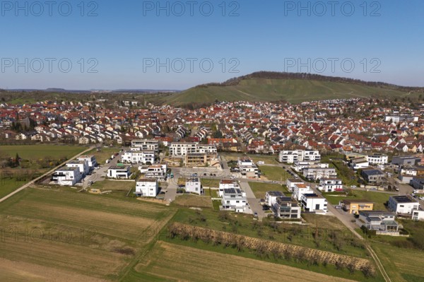 View of city with new development area, red roofs and surrounding green hills in the background,