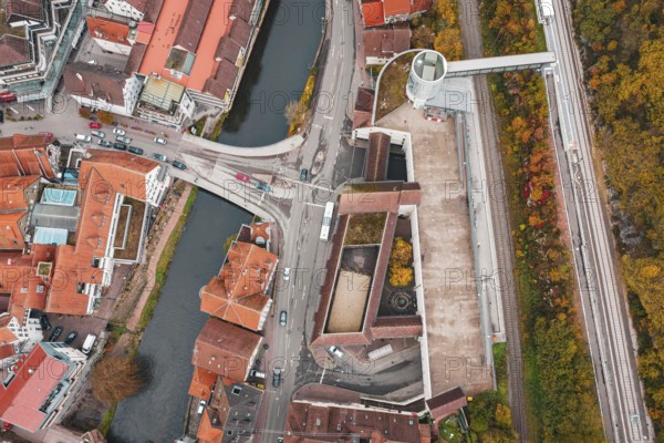 Aerial view of a city with a river and bridges, surrounded by autumn-colored trees, ZOB Calw,