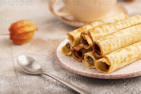 Waffles with caramel on brown concrete background and orange linen textile, cup of coffee, side