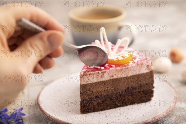 Chocolate cake with hand on brown concrete background, cup of coffee, side view, close up,