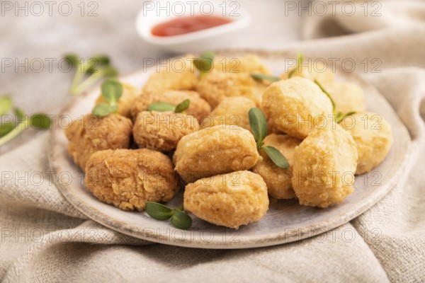 Fried crispy Chicken Nuggets with ketchup, microgreen on brown concrete background and linen