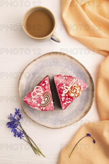 Chocolate cake on white wooden background and orange linen textile, cup of coffee, top view, flat
