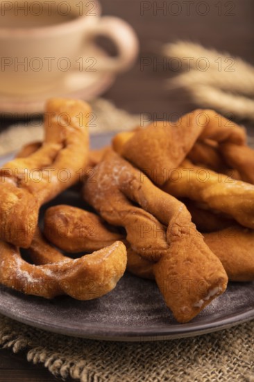 Crunchy biscuit Brushwood cookies sprinkled with powdered sugar on brown wooden background and