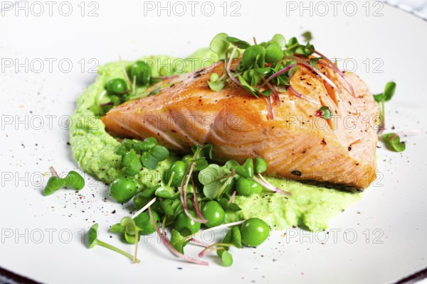 Delicious grilled salmon is placed elegantly on creamy green pea puree. Fresh microgreens and peas