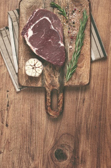 Raw steak, beef steak, rib eye steak, on a cutting board, freshly frozen, with spices and herbs, on