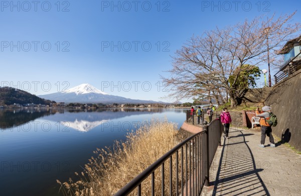 Tourists take pictures on the waterfront, Volcano Mt. Fuji is reflected in Lake Kawaguchi,