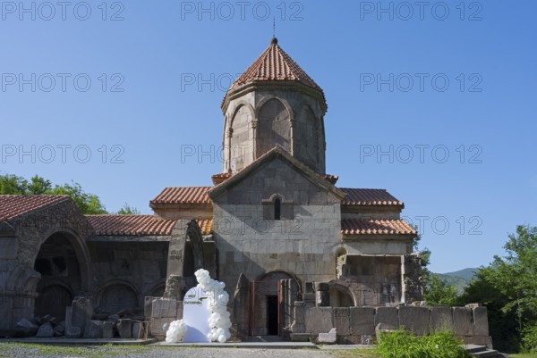 Historic church with tiled roof and blue sky in the background surrounded by greenery, Wahanavank