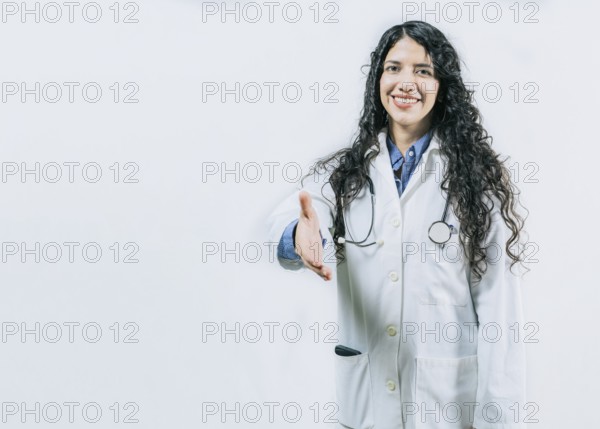 Smiling female doctor gesturing welcome, isolated. Latin female doctor shaking hands at the camera