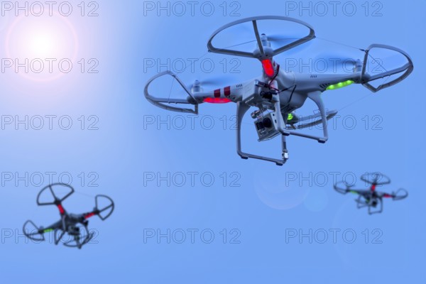 Three miniature quadcopter drones, teleoperated unmanned aerial vehicles, UAV equipped with cameras