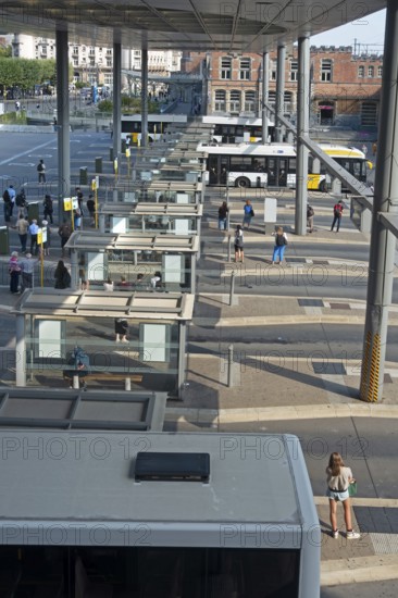 Commuters waiting for transit buses at bus stop of public transport company De Lijn at train