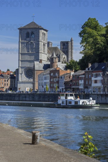 16th century Gothic Notre-Dame collegiate church and riverboat on the Meuse river in the city Huy,