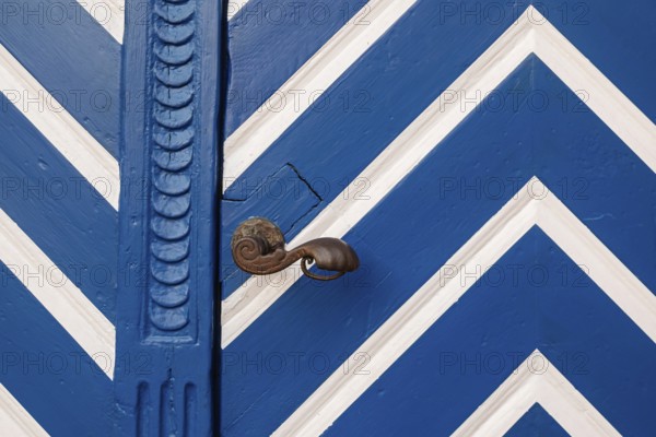 Blue door with white zigzag pattern and antique door knob, Münsterland, North Rhine-Westphalia,