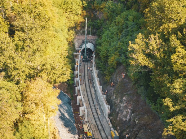 Tunneling for railroad tracks in an autumn forest area with construction workers and machines,