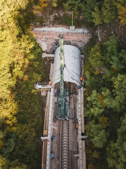 Drone photo of a crane working on a tunnel structure in an autumn environment, built by Hermann,
