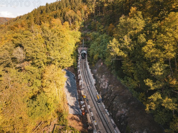 Layered view of an autumn rail construction site in the forest with construction vehicles,