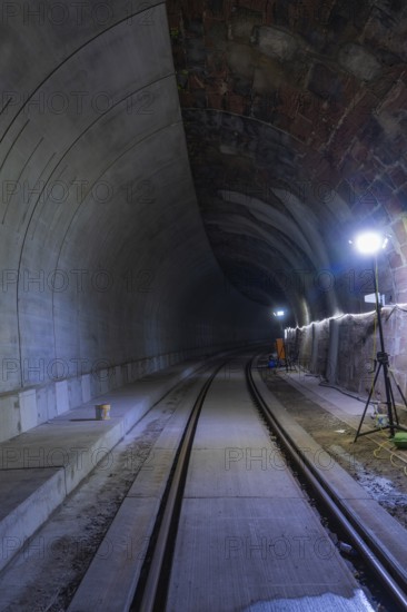 Tunnel with rails and bright lighting along the wall, dark building atmosphere, Hermann building,