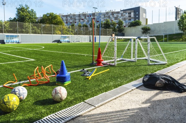 Artificial grass soccer field with multiple training equipment including cones, hurdles, a small