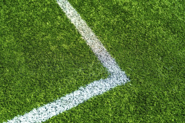 Green artificial turf creating a textured background with a white painted line marking a corner of