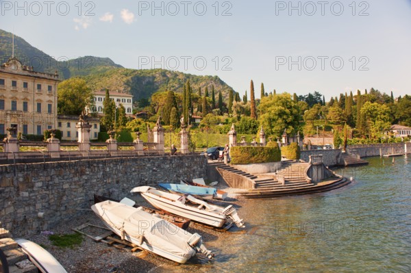 Waterfront with old villa, beautiful plants, trees and boats on Lake Como, Italian Lago di Como,