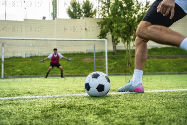 Football player preparing to shoot a penalty kick with the ball on the artificial turf, facing a
