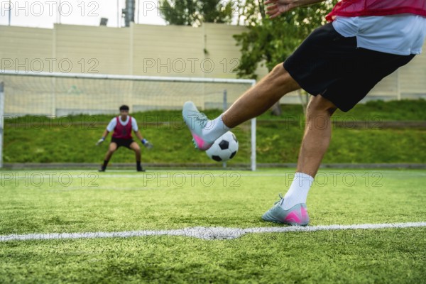 Soccer player preparing to kick a penalty shot towards the goal, with a vigilant goalkeeper in