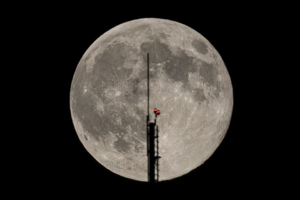 The full moon passes through the antenna on the roof of the European Central Bank (ECB), Frankfurt