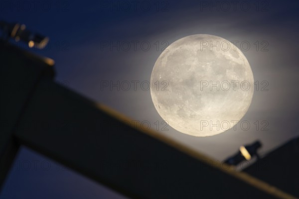 The full moon sweeps along the Frankfurt evening sky and passes the pillars of the rafter bridge,