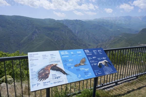An observation deck with information boards about eagles shows a view of a mountainous landscape