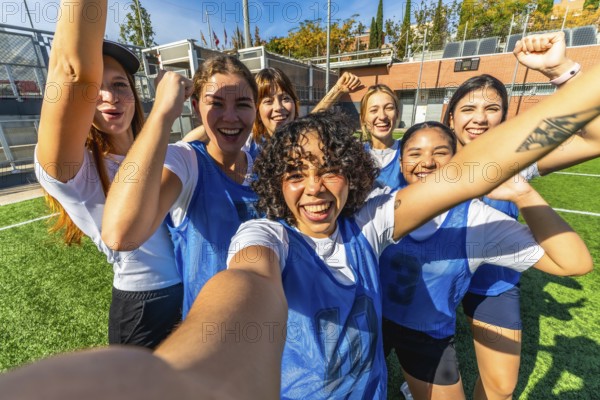 Diverse group of young women soccer players celebrating an achievement or victory, taking a joyful
