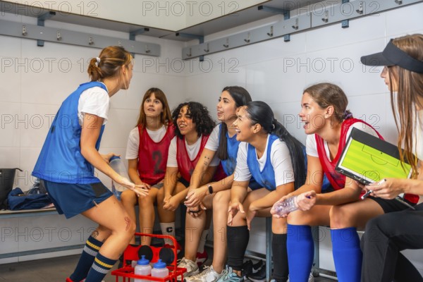 Women's soccer team players are attentively listening to their coach explaining game strategy and a
