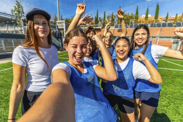 Group of young, multiracial women soccer players cheering and taking a joyful selfie on sunny green