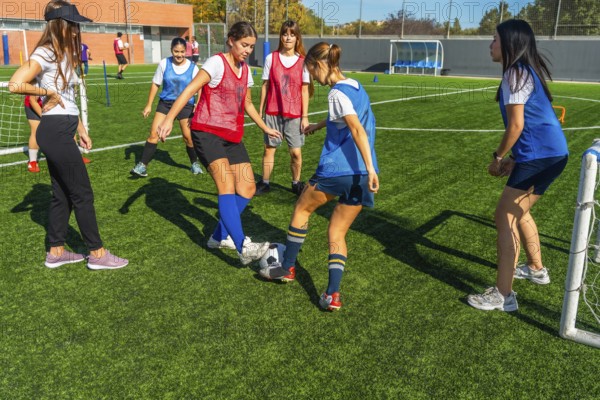 Young women soccer players are practicing passing and dribbling drills on a green artificial turf