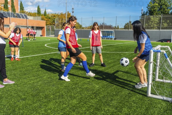 Young females training soccer on an artificial turf field, engaging in a small sided game with a