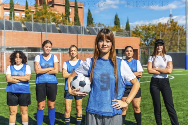 Diverse women's soccer team standing together on a sunny outdoor pitch, confident and ready to