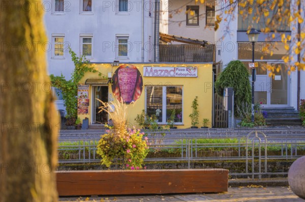 Yellow pizza building on a sunny street surrounded by autumn plants, Aidlingen, Böblingen district,