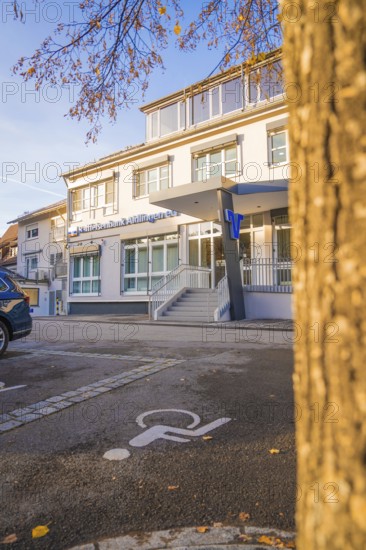 Modern building complex with parking lot and wheelchair-friendly markings, autumnal atmosphere,