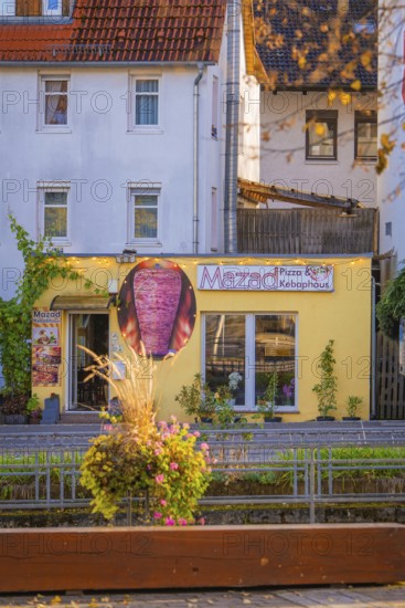 Small pizzeria with yellow façade in the midst of a colorful autumn backdrop, Aidlingen, Böblingen