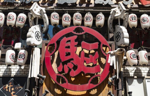 Red sign with Japanese characters, bar entrance decorated with lanterns, Shinjuku City, Tokyo,