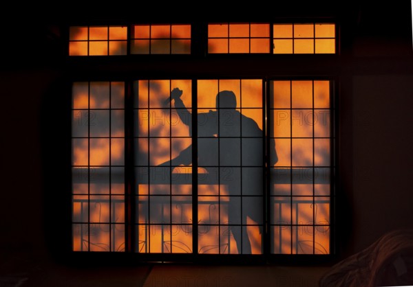 Shadow of a man climbing over balcony railings, burglar with knife, assassin, ninja, on the balcony