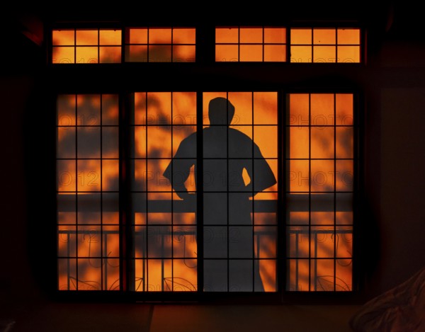 Shadows of a man in kimono, on the balcony behind sliding shoji doors in a traditional Japanese