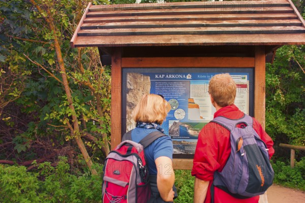 Tourist couple in front of information board of Cape Arkona, coast of Rügen, largest German island,