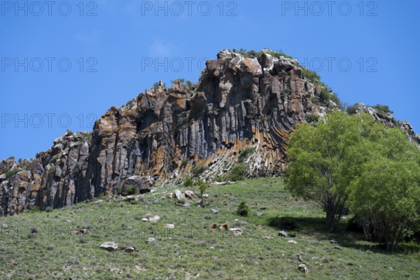 Mighty rock formation with lush greenery and clear skies, radiating peace and natural beauty,