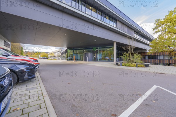 Parking lot in front of a modern, grey office building under clear skies, Calw District Office,