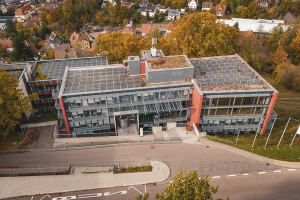 Modern office building with solar panel on the roof and surrounding autumn trees, Calw District
