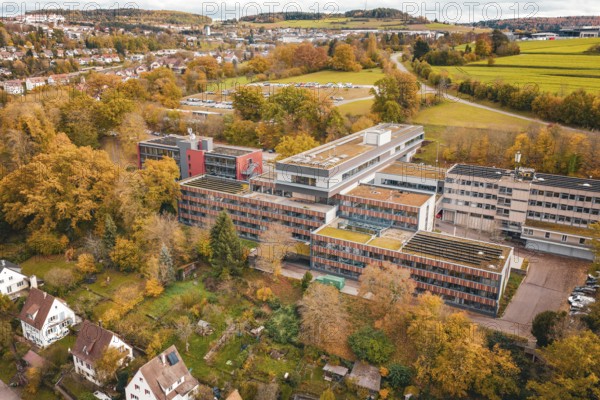 Multi-storey building complex with colorful autumn trees in rural surroundings, Calw District