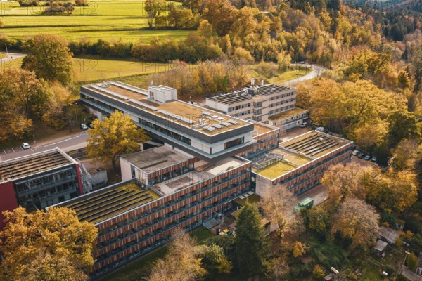 Building complex in a hilly, autumnal area with flat roof and solar cells, Calw District Office,