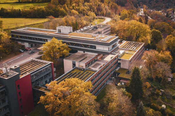 Autumn aerial view of a large building complex in the middle of forest and village, Calw District
