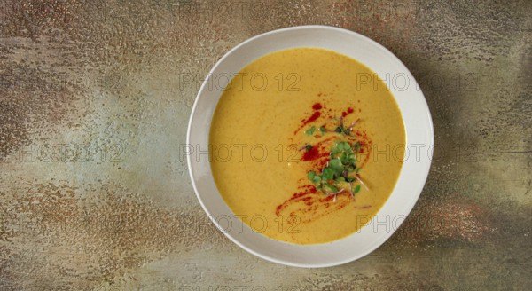 Pumpkin cream soup, in a white bowl on a textured background, top view, homemade, no people, rustic