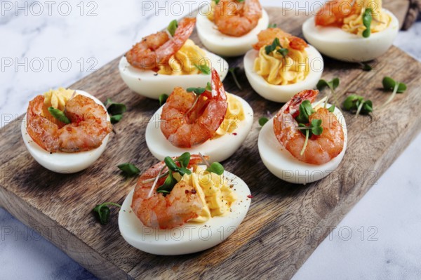 Boiled eggs stuffed with yolk and seasoned with mayonnaise, stuffed eggs with shrimp, on a wooden